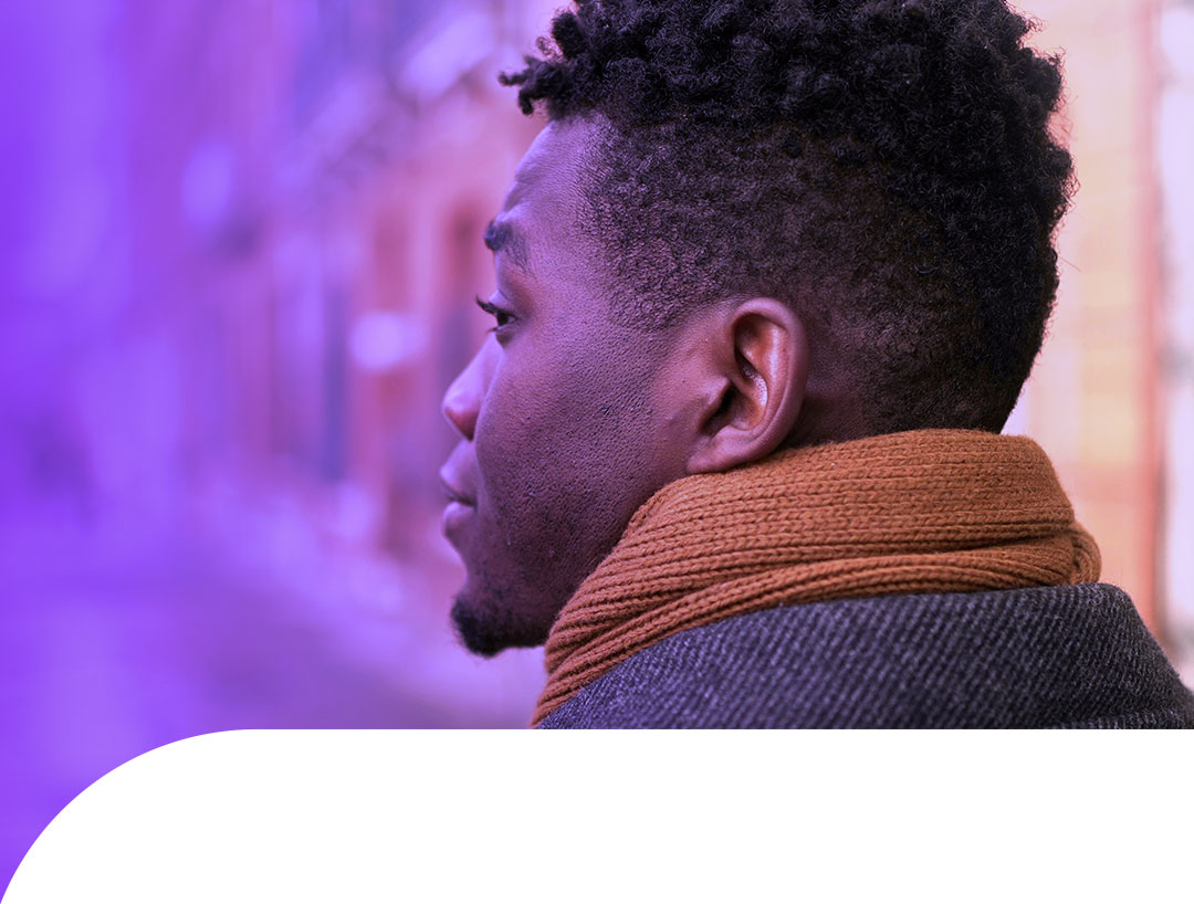 A person with autism viewed from behind standing on an urban street with their back to us.