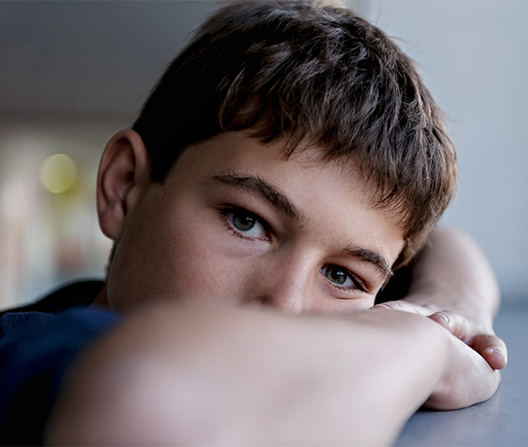 Child leaning on the desk with his elbows on the table.